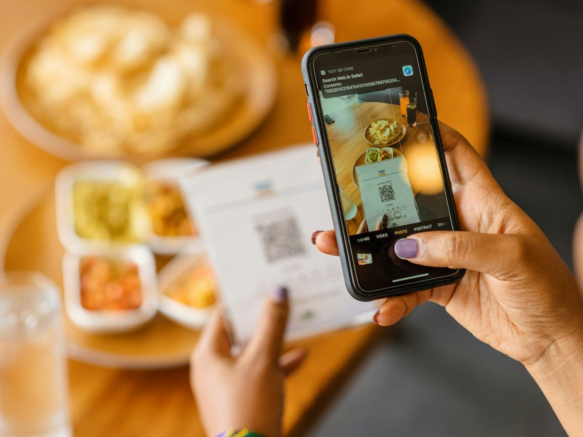 Cliente lendo com o celular o QR Code de pagamento na mesa de um restaurante.